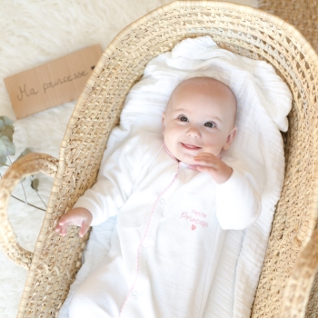 baby girl lying down and dressed in the newborn velvet pajamas in white and pink "little princess"