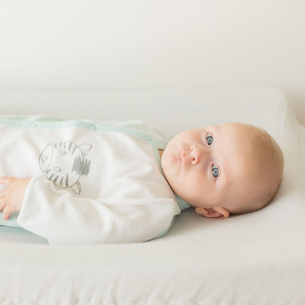 Bebé niño acostado con su pijama nacimiento blanco y azul cebra