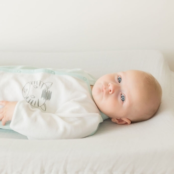 Babyjongen liggend met zijn witte en blauwe zebra geboortepyjama Babyjongen liggend met zijn witte en blauwe zebra geboortepyjama