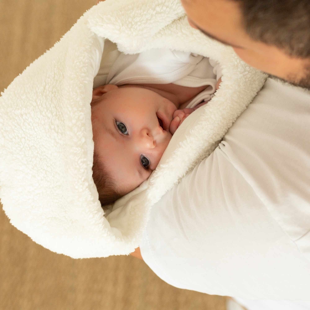 Dad carrying his baby snugly wrapped in a footmuff