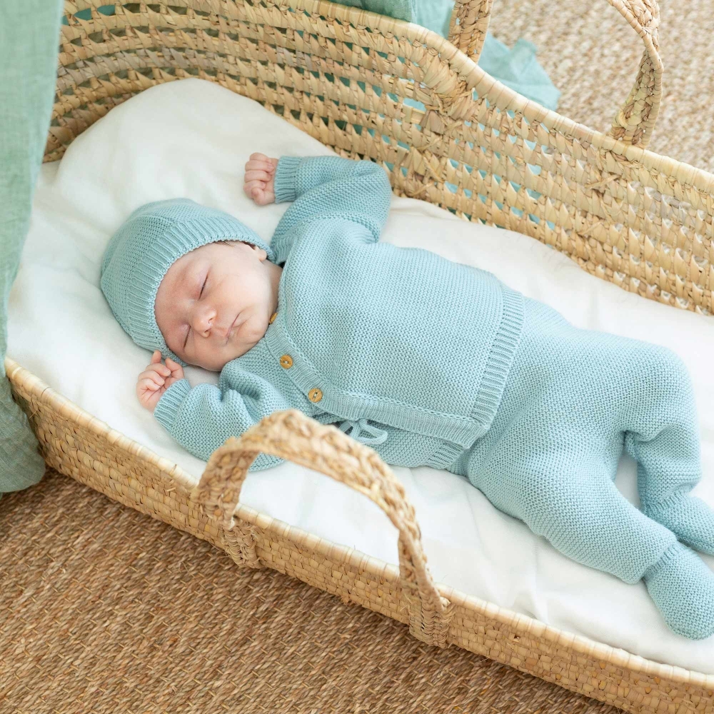 Bébé allongé dans le couffin avec l'essemble complet en maille sauge Bébé allongé dans le couffin avec l'essemble complet en maille sauge