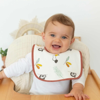 Bebé a sorrir com o seu babete na cadeira alta