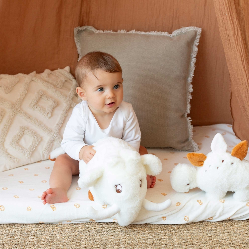 Bebè che gioca con il suo peluche musicale nel suo spazio giochi