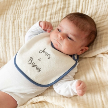 Neonato con il suo bavaglino blu navy intorno al collo