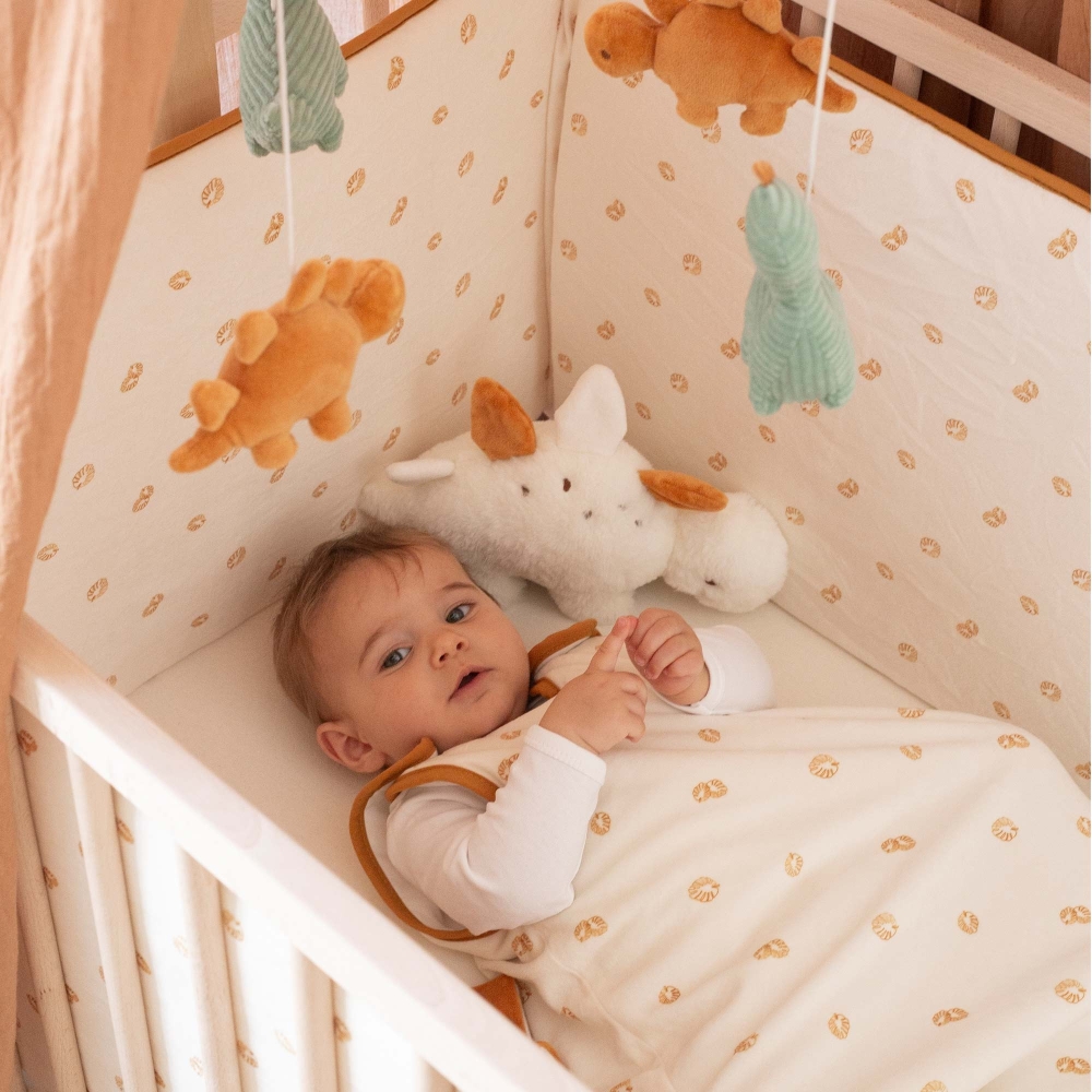 Bebé no seu saco de dormir a brincar no berço