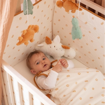 Bebé no seu saco de dormir a brincar no berço