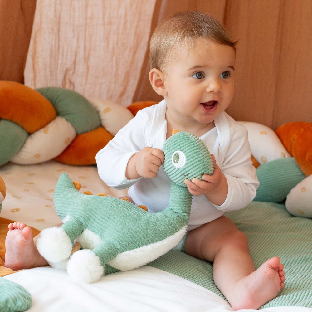 Baby die speelt met zijn muzikale knuffel diplodocus Baby die speelt met zijn muzikale knuffel diplodocus