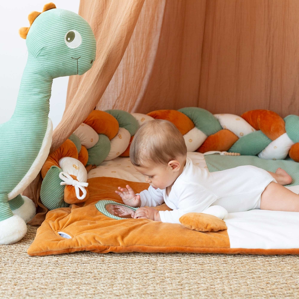 Baby looking at themselves in the mirror with their large diplodocus plush toy beside them Baby looking at themselves in the mirror with their large diplodocus plush toy beside them