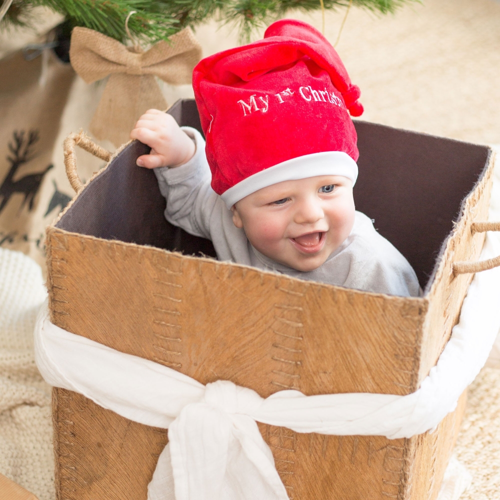 bambino gioca in una scatola regalo di Natale con il suo cappello di Natale bambino gioca in una scatola regalo di Natale con il suo cappello di Natale