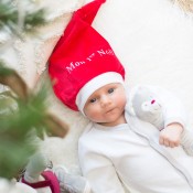 Bebé com o seu gorro de Natal e o seu boneco de conforto