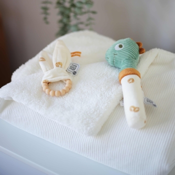 White folded blanket with developmental toys placed on top
