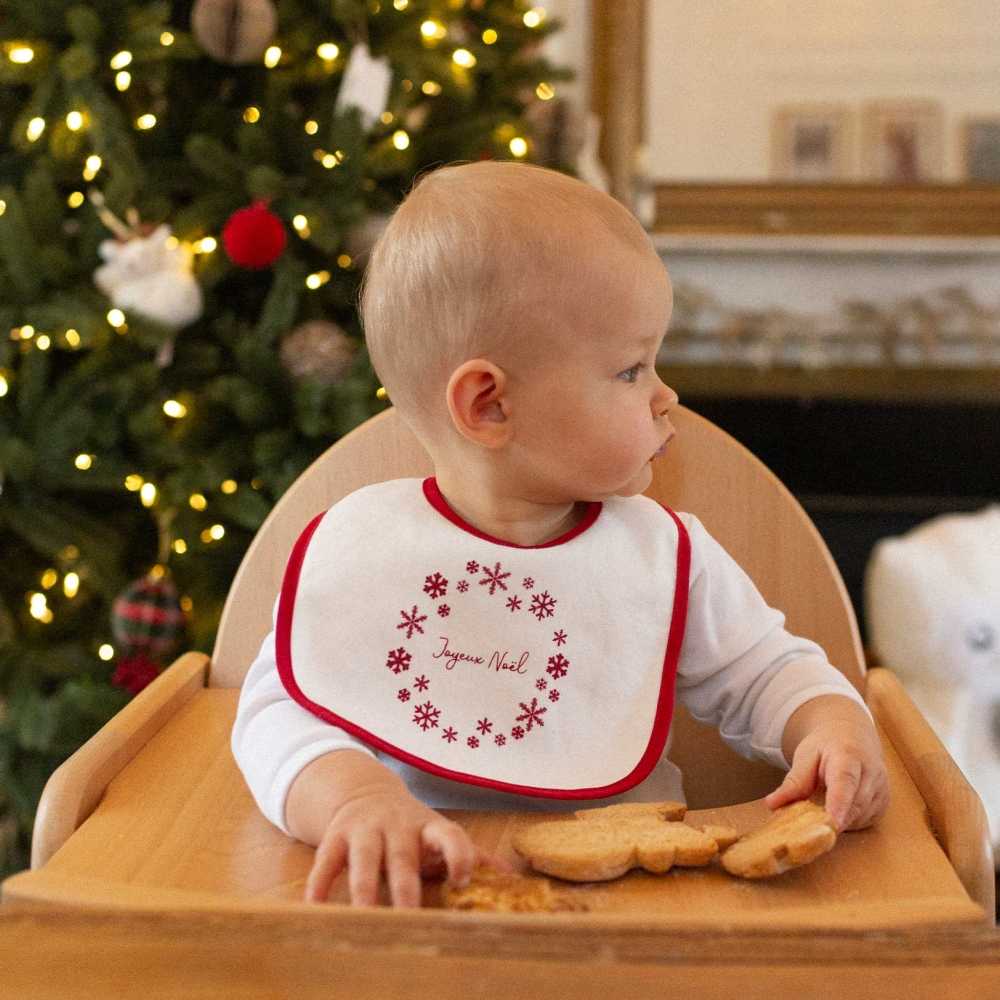 bebé com babete de natal e o seu biscoito
