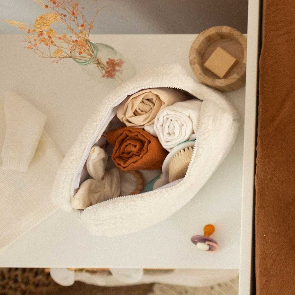 Bolsa de higiene para bebé aberta com os artigos essenciais para o bebé.