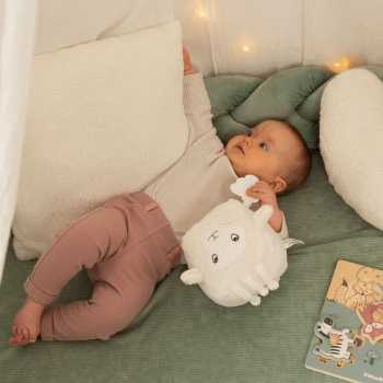 Bebé menina a brincar com o cubo de atividades Wooly, a ovelha, num espaço de brincadeira