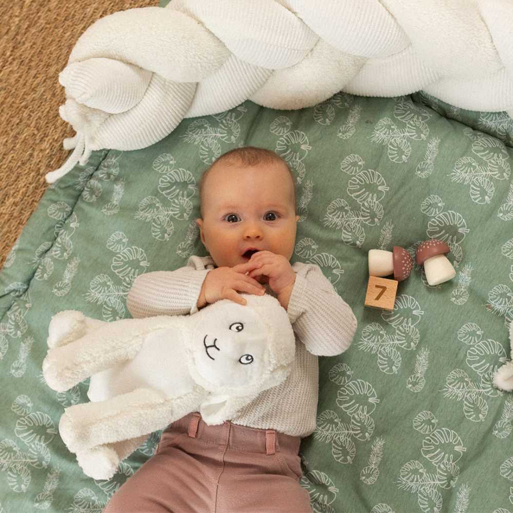 bebé com a sua peluche carneiro no seu tapete de atividades