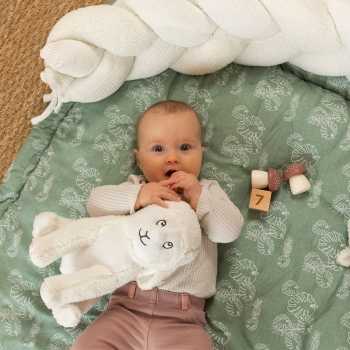 bebé com a sua peluche carneiro no seu tapete de atividades