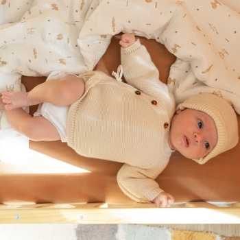 Baby in seinem Bett mit seinem Strick-Jäckchen