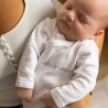 bebé usando o body Trois kilos sept nos braços da sua mamã