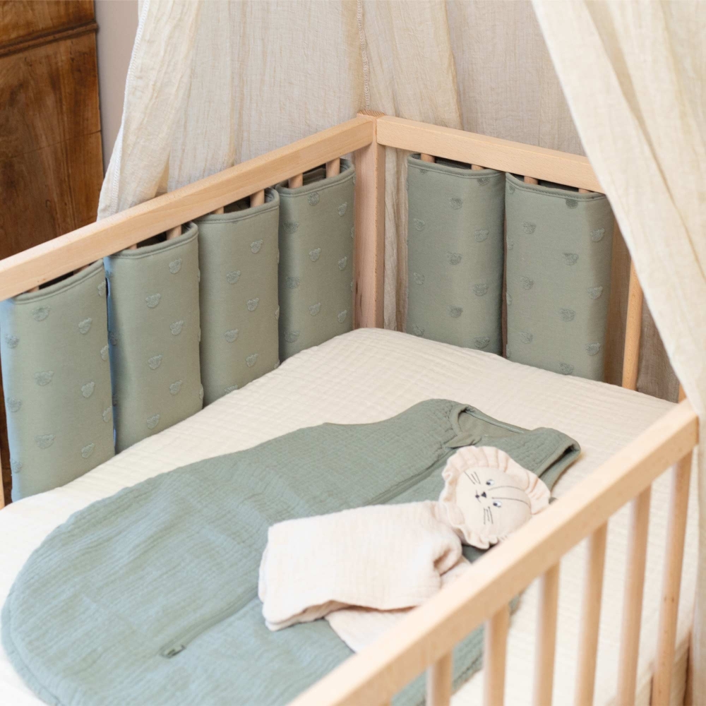 cuna de bebé con ropa de cama y protector de barrotes