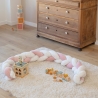 White decorative braid and pink flowers delimit the baby play area