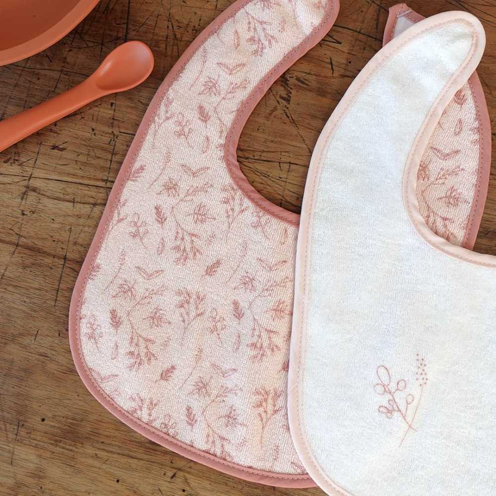 Pormenor dos motivos dos babetes para os primeiros meses em rosa e branco Pormenor dos motivos dos babetes para os primeiros meses em rosa e branco