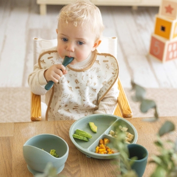 Baby isst und hilft sich mit seinem Silikonlöffel