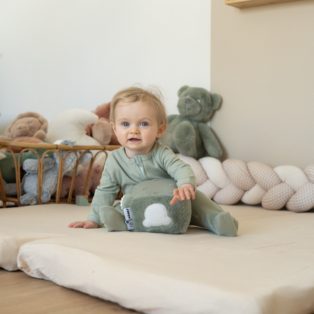 bebé a brincar com um cubo de atividades, vestido com um pijama de algodão verde-sálvia