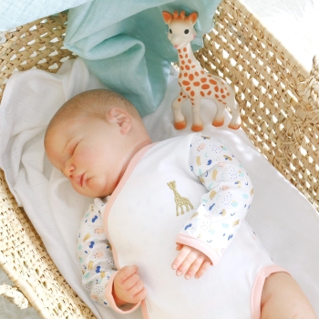 bimbo che dorme nella sua culla con il suo body da bambina ricamato