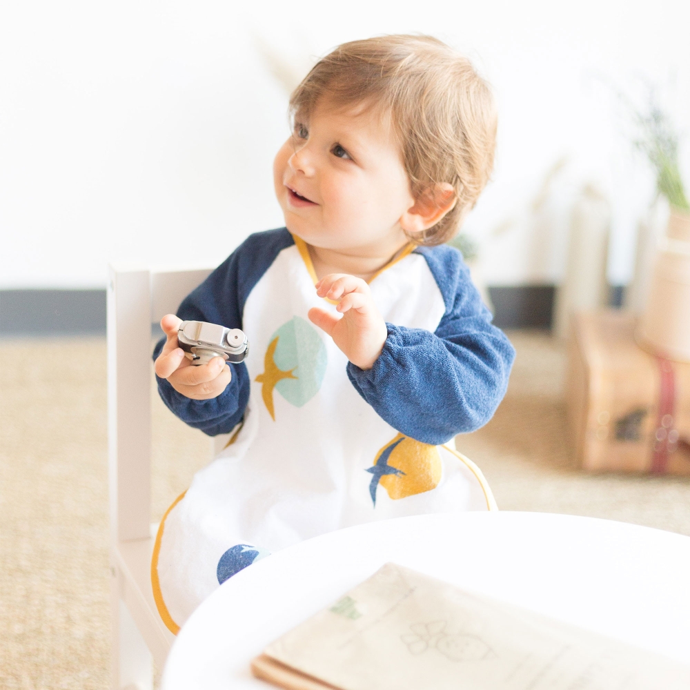 Baby with navy blue sleeved terry cloth bib apron