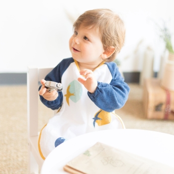 Baby mit seiner Frottee-Schürze mit Ärmeln marineblau