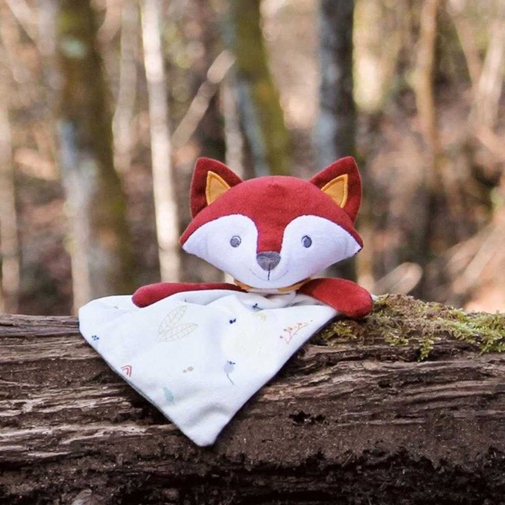 Doudou renard mis en scène sur un tronc d'arbre