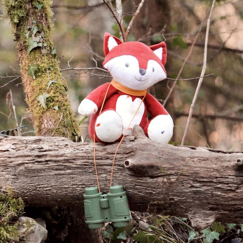 Musical fox plush sitting on a tree trunk in the forest Musical fox plush sitting on a tree trunk in the forest