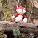 Musical fox plush sitting on a tree trunk in the forest Musical fox plush sitting on a tree trunk in the forest