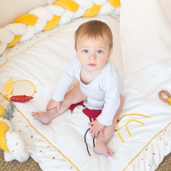 Little girl sitting on her play mat surrounded by the decorative braid