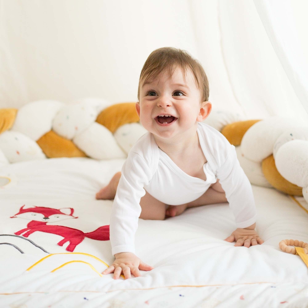 Bebé niño sobre alfombra de actividades riéndose