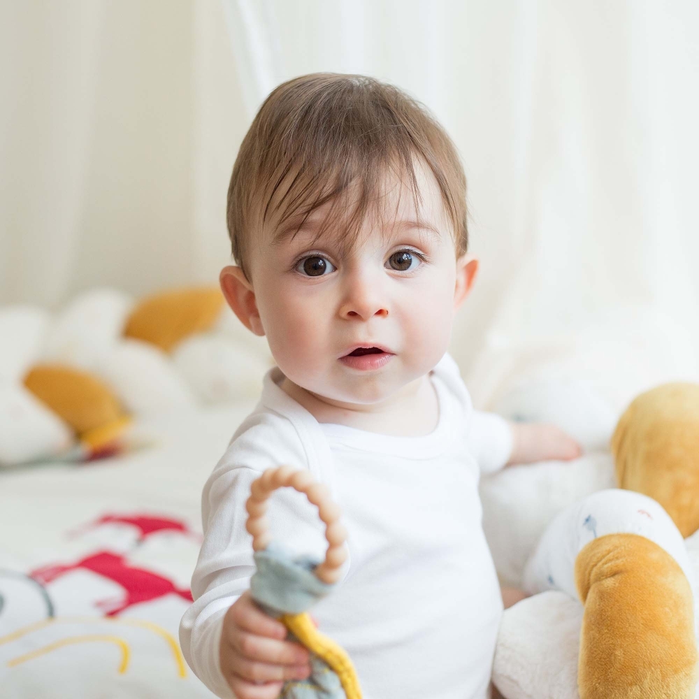 Bébé avec hochet de dentition sur son tapis d'éveil