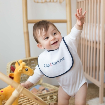 Baby Junge der sich mit seinem Lätzchen amüsiert