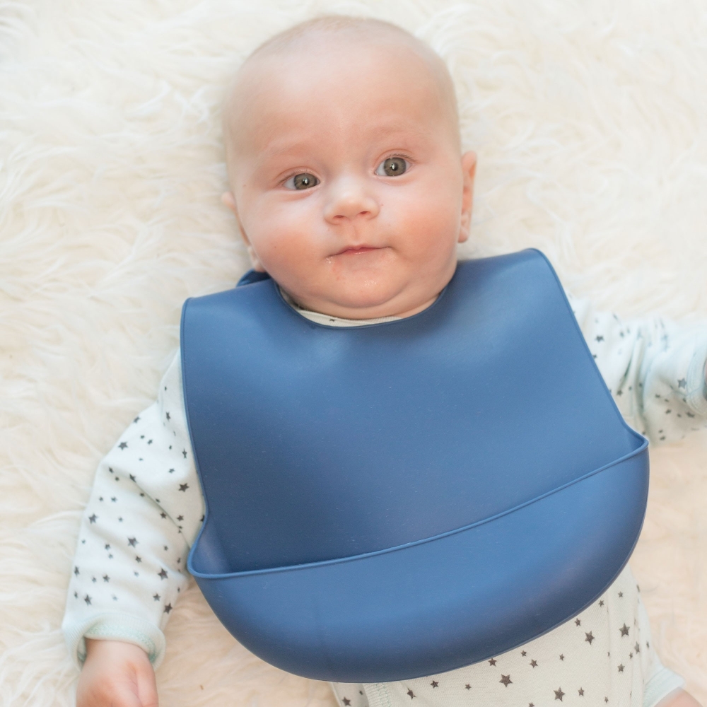 Baby with its very cute navy blue silicone bib Baby with its very cute navy blue silicone bib