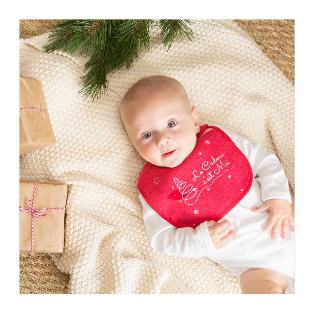 Bébé avec son bavoir de Noël et les cadeaux du papa Noël