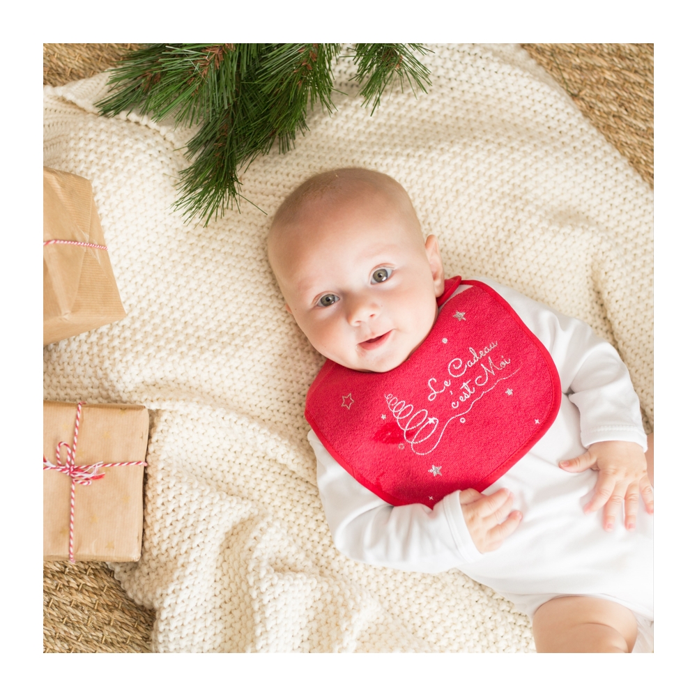 Bebè con la sua bavetta natalizia e i regali di Babbo Natale Bebè con la sua bavetta natalizia e i regali di Babbo Natale