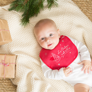 Bébé avec son bavoir de Noël et les cadeaux du papa Noël