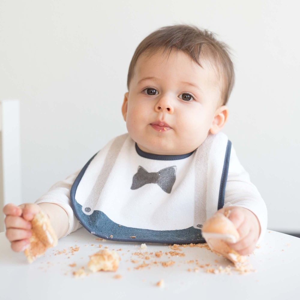 Bambino che mangia la sua torta protetto dal suo bavaglino da gentiluomo Bambino che mangia la sua torta protetto dal suo bavaglino da gentiluomo