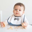 Bambino che mangia la sua torta protetto dal suo bavaglino da gentiluomo Bambino che mangia la sua torta protetto dal suo bavaglino da gentiluomo