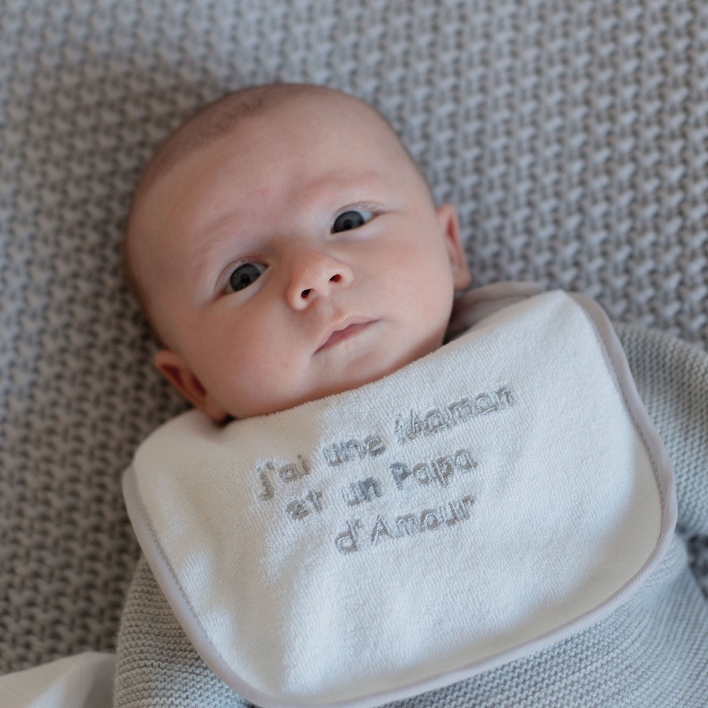 Bébé et son bavoir gris avec un petit message trop mignon