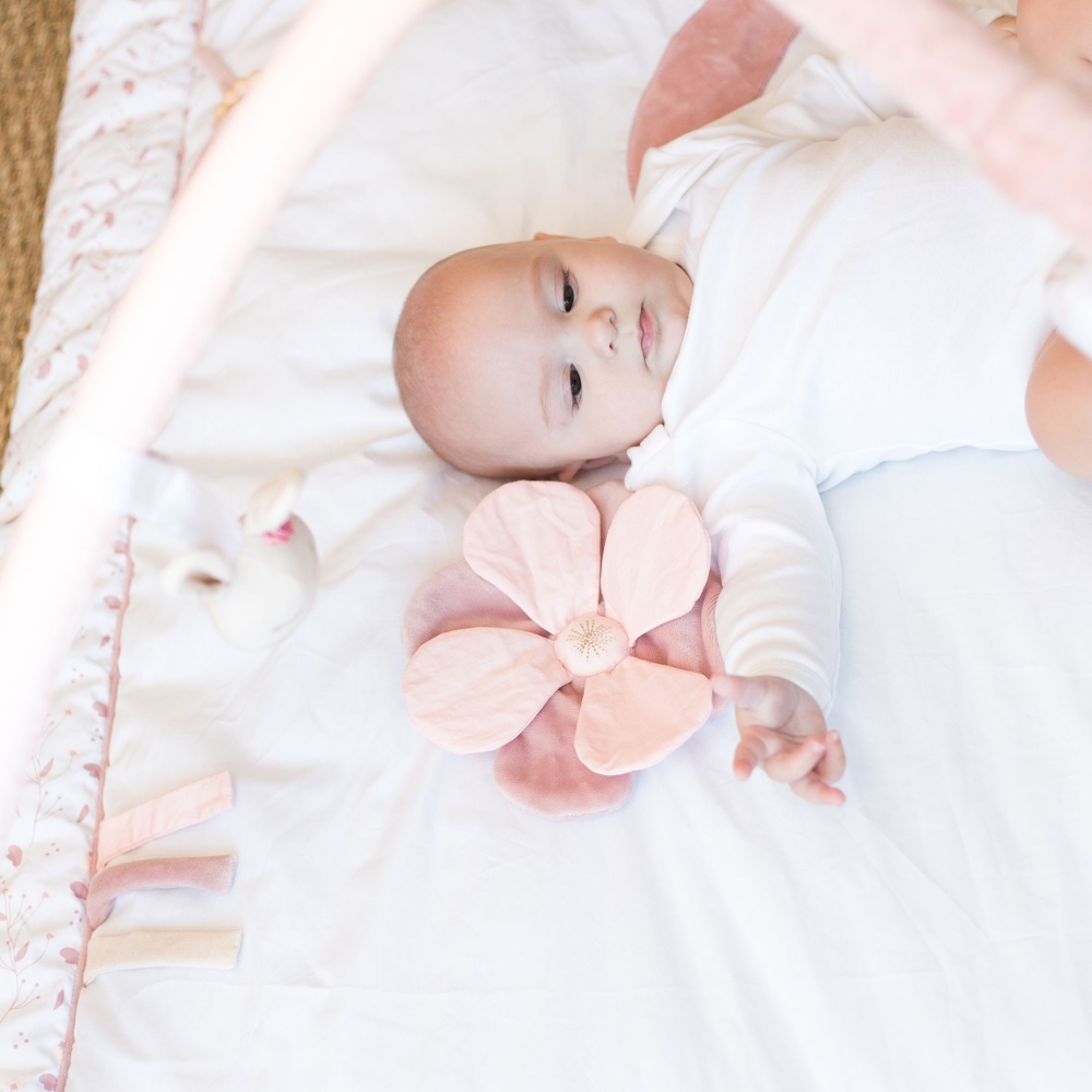 Baby op zijn mooie roze en witte speelkleed met de activiteitenbogen Baby op zijn mooie roze en witte speelkleed met de activiteitenbogen