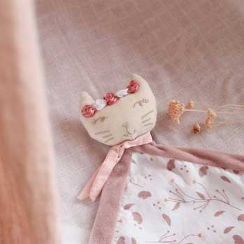 peluche rosa pousado na cama do bebé com uma pequena flor decorativa