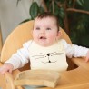 Bébé sur sa chaise haute avec son bavoir sable petit chat Bébé sur sa chaise haute avec son bavoir sable petit chat