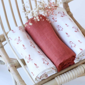 Mise en scène avec le lot de langes sur une petite chaise en rotin pour bébé Mise en scène avec le lot de langes sur une petite chaise en rotin pour bébé