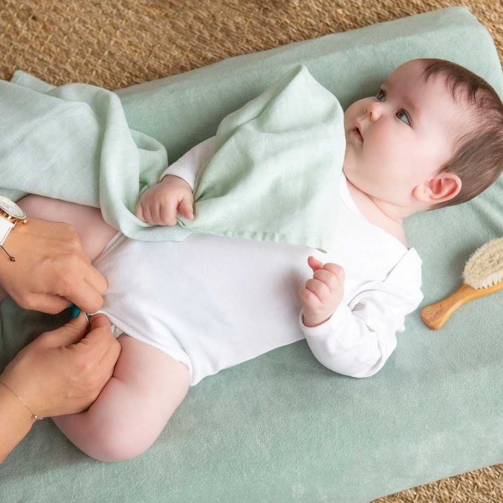 bebé com a sua fralda de pano verde-água estampada da coleção Au large de Nova