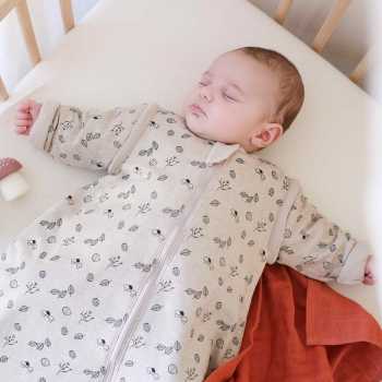Bebé a dormir bem quentinho na sua cama e no seu saco de dormir com mangas floresta